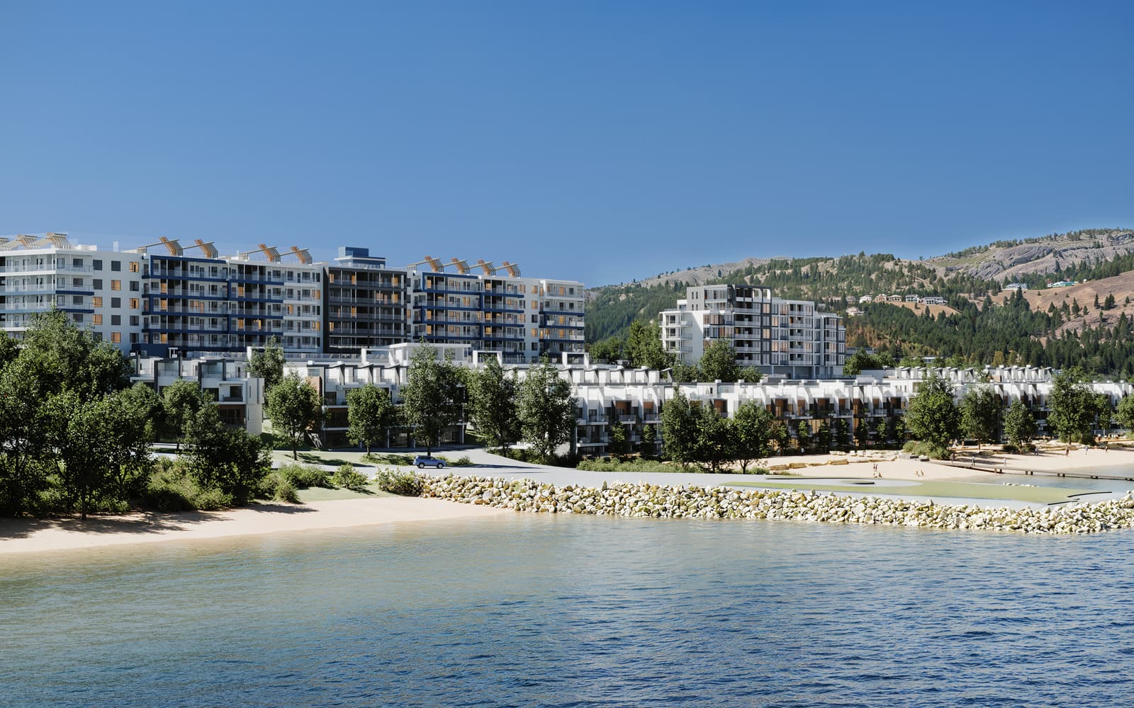 Westrich Bay from Okanagan Lake on a summer day: the beach and rock breakwater, the villas, the Waterfront Tower and the rental buildings below the West Kelowna hills