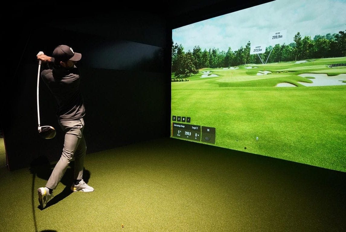 Golfer mid-swing at the indoor golf simulator