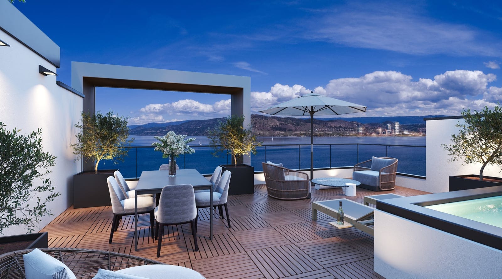 A villa rooftop terrace in the evening: dining table, lounge chairs, an umbrella and a hot tub, with Okanagan Lake and downtown Kelowna beyond